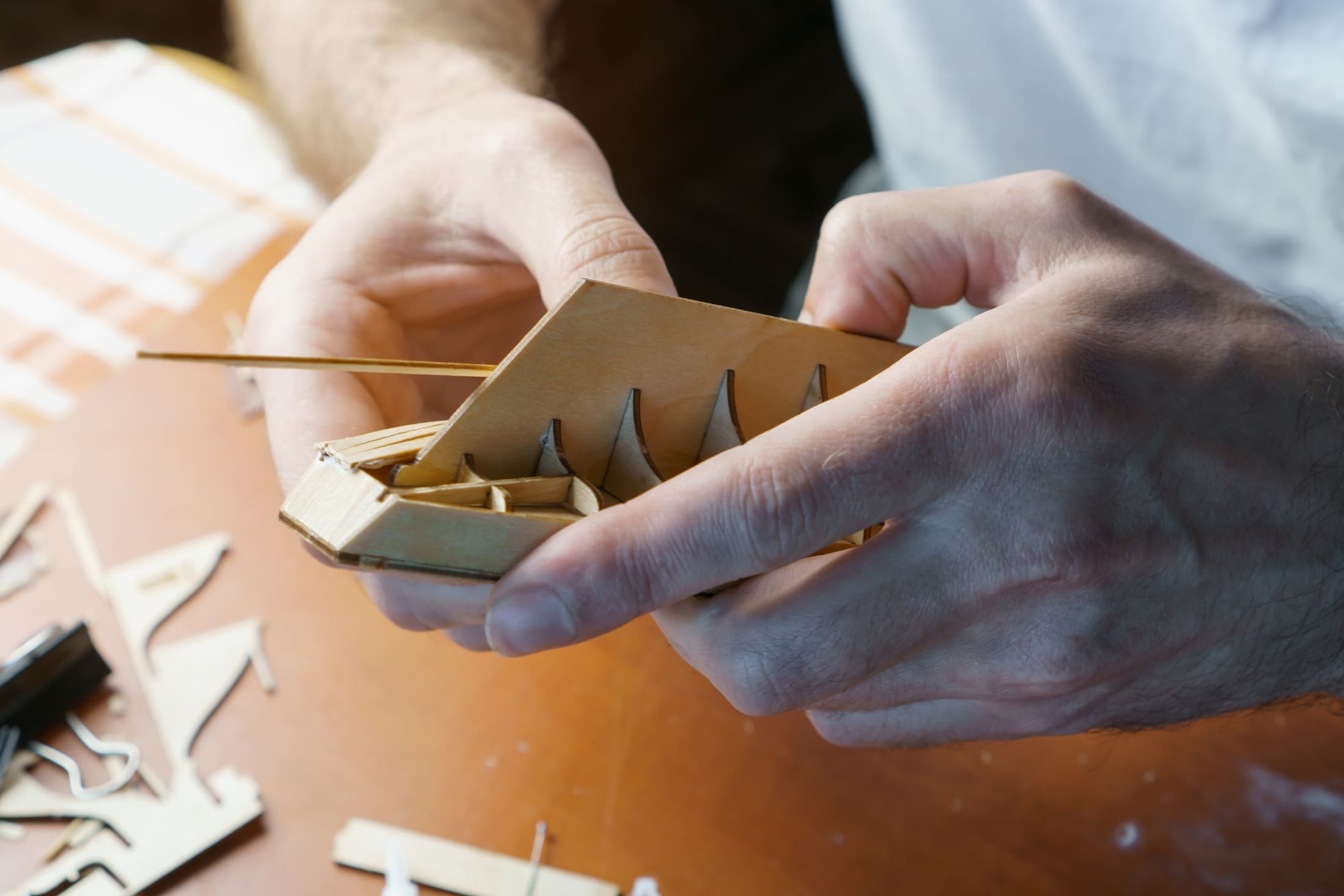 Modeler applying outer planking on wooden ship hull